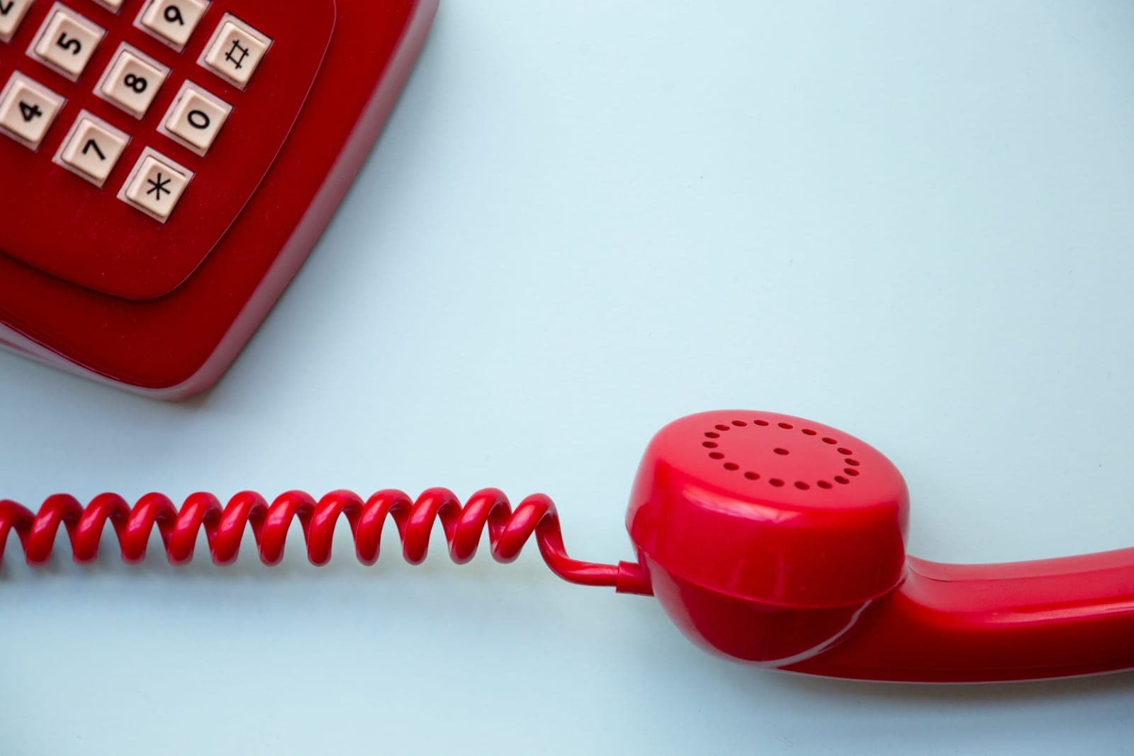 Red retro telephone on light blue background
