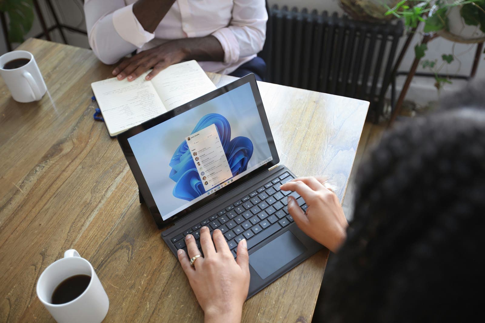 Persoon typt op een Windows-laptop met een kop koffie ernaast